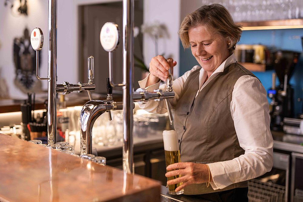 Eine Mitarbeiterin zapft frisches Bier an der Bar des Gasthofes Goldgasse